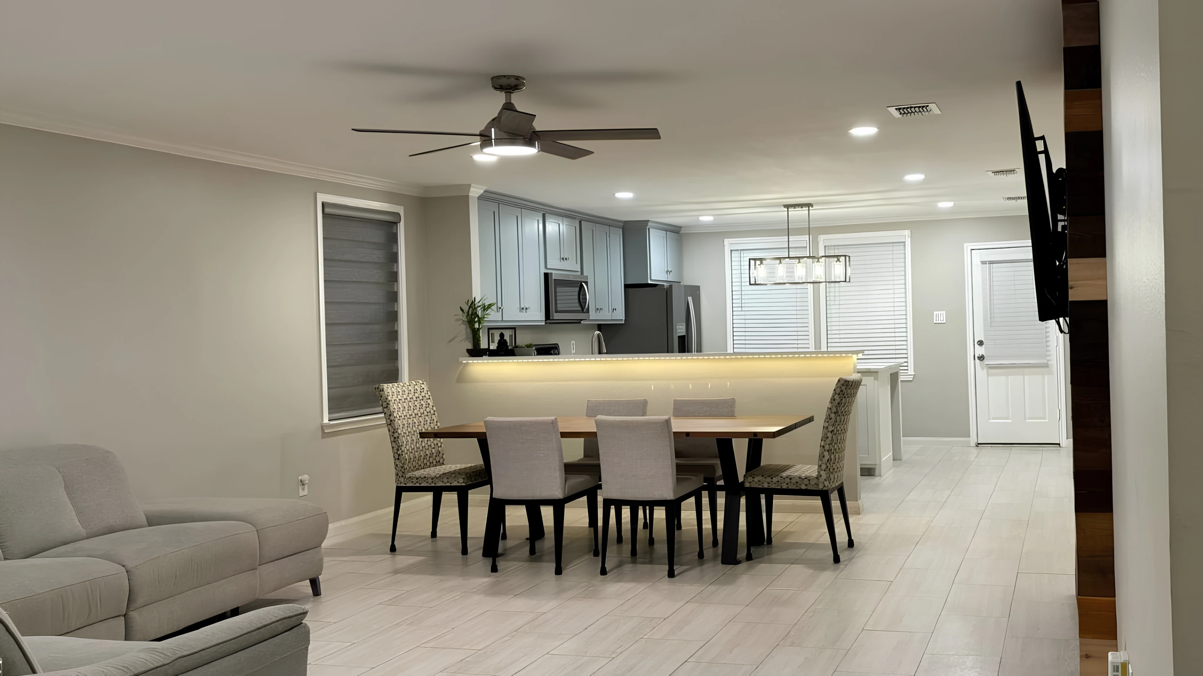 Sala y comedor integrados en un espacio abierto, con sofá gris, mesa de comedor y luz natural